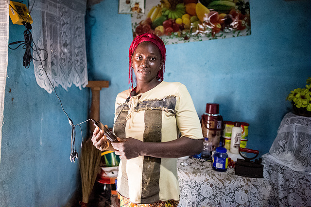 A consumer charges her phone through her SHS after entering a PAYG code