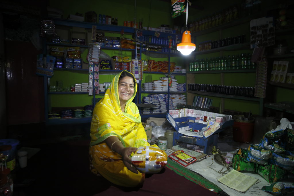 A shopkeeper in Bangladesh works by the light of a solar lantern