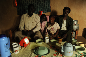 Mrs Cheruyiot with her husband and children at their home, their S250 lamp charging behind them © Lighting Africa