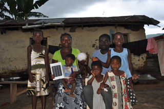 The Danquah family outside their home in Nimforkrom, Ghana showing off a solar panel and a versatile lamp that has lit up their nights and changed their lives Â©Lighting Africa