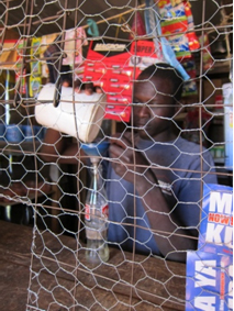 A shopkeeper measures kerosene for sale by the coke bottle © Jennifer Tracy/Lighting Africa